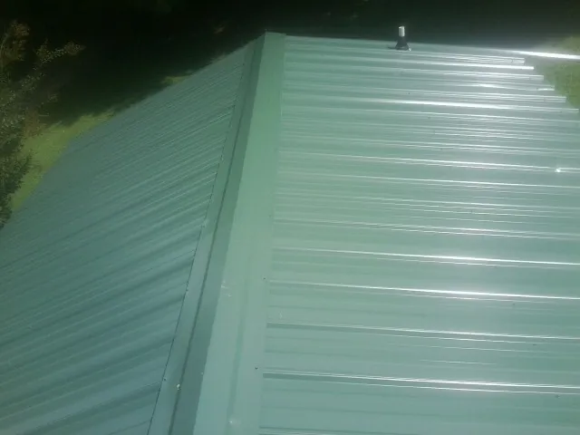 New green metal panels meeting at the ridge of a roof — Flat Roof Repair work by our crew in Belmont